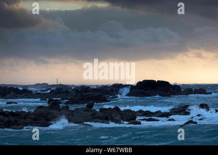 Meneham pittoresque côte rocheuse et phare de stormy sunset en région Bretagne en France Banque D'Images