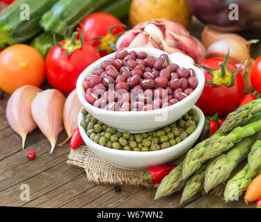 Les haricots azuki et Mungo dans un bol et les légumes sur la table en bois Banque D'Images