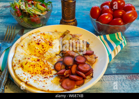 Oeufs brouillés avec bacon, l'oignon et les saucisses. Sur une plaque sur la table. Banque D'Images