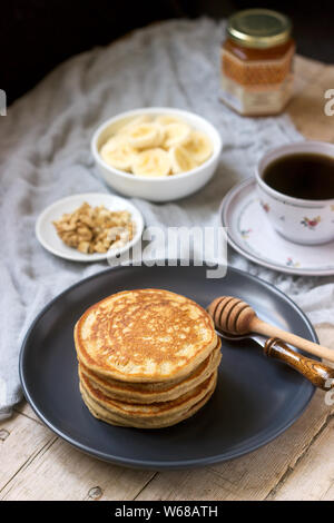 Pancakes à la banane, noix et miel, servi avec du thé. Style rustique. Banque D'Images