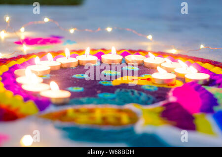 Belle rangoli fabriqués à partir de poudres colorées et décorées de bougie de cire de diyas sur diwali eve. Ces modèles sont fabriqués à la main par les hindous et décorer Banque D'Images