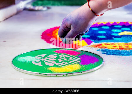 Main de jeune indienne faisant rangoli à partir de poudre de couleur sur le diwali eve. Ces magnifiques créations sont faites dans chaque maison hindoue pour décorer et de célébrité Banque D'Images