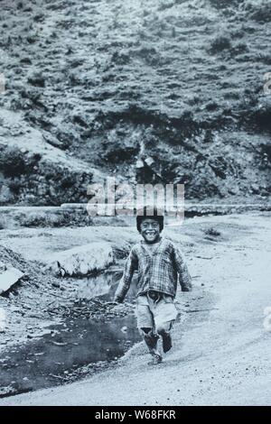 Noir et blanc Fine art Photography à partir des années 1970 d'un jeune garçon très heureux hispanique tourne autour de l'accidenté. Banque D'Images