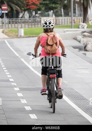 Vue arrière d'une femme en vélo sur la piste cyclable de la ville en Espagne Banque D'Images