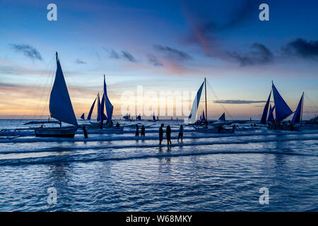 Paraws traditionnels (Bateaux à voile) sur une croisière au coucher du soleil off White Beach, Boracay, Province d'Aklan, Philippines. Banque D'Images