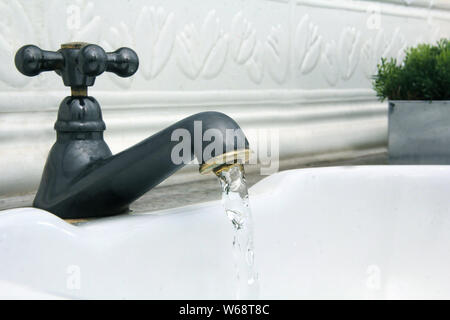 L'eau qui sort du robinet dans l'évier blanc Banque D'Images