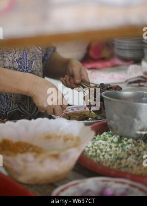 Vendeur préparant le satay de chèvre dans un magasin traditionnel à Kediri, Indonésie Banque D'Images