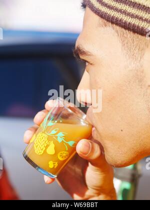 Un jeune homme boit un verre de fines herbes javanais Banque D'Images