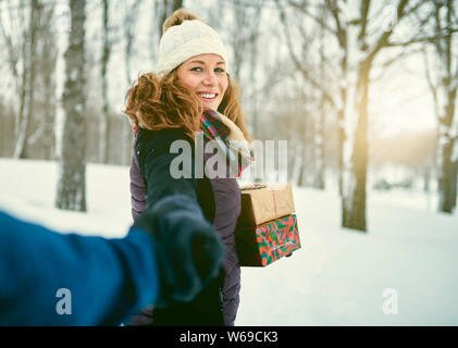 POV'image d'un couple holding diversifié des cadeaux de Noël tout en marchant à travers une forêt d'hiver Banque D'Images