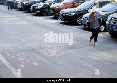 Un piéton utilise son smartphone comme elle marche sur le trottoir mobile lane à Xi'an, ville du nord-ouest de la Chine, dans la province de Shaanxi, du 5 juin 2018. Chin Banque D'Images