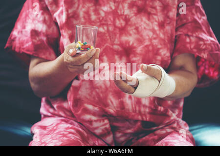 Senior asian woman prendre comp medicine on hand while sitting on sofa at home Banque D'Images