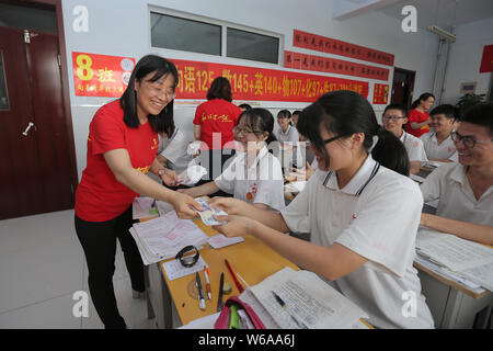 Les enseignants chinois distribuer 5-yuan billets comme la chance de l'argent à leurs étudiants qui vont se présenter à l'examen d'entrée du collège national annuel, également connu sous le nom de ga Banque D'Images