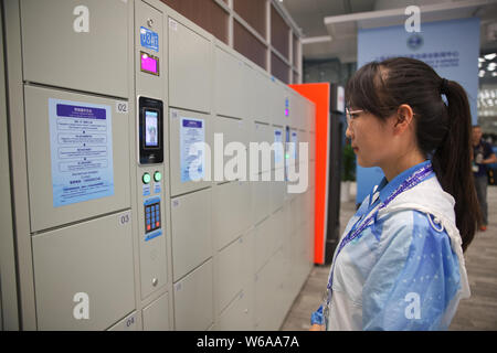 Un bénévole démontre l'ouverture d'un casier intelligente par la reconnaissance faciale au centre des médias pour le 18e Sommet de l'Organisation de coopération de Shanghai Banque D'Images