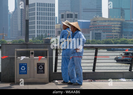 Les travailleurs chinois se protéger avec des chapeaux d'un soleil de plomb comme ils travaillent sur le Bund à Shanghai, Chine, 26 juin 2018. Météo Shanghai bure Banque D'Images