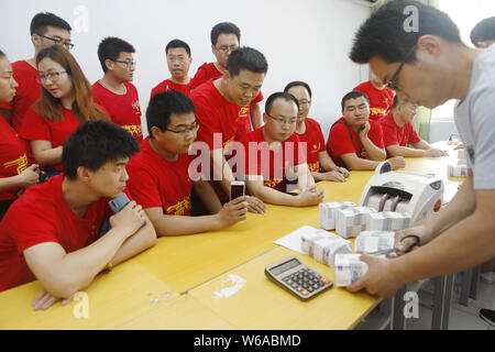 Les enseignants chinois queue pour recevoir 5-yuan billets qui sera donné aux étudiants qui vont se présenter à l'examen d'entrée du collège national annuel, également Banque D'Images