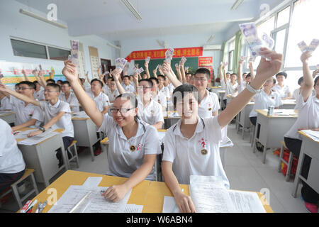 Des étudiants chinois qui vont se présenter à l'examen d'entrée du collège national annuel, également connu sous le gaokao, réagissent comme ils peuvent contenir jusqu'à 5 yuan billets en euros qui leur est donné comme Banque D'Images