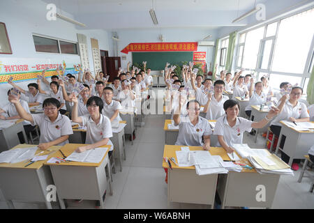 Des étudiants chinois qui vont se présenter à l'examen d'entrée du collège national annuel, également connu sous le gaokao, réagissent comme ils peuvent contenir jusqu'à 5 yuan billets en euros qui leur est donné comme Banque D'Images