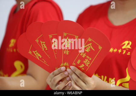 Un enseignant chinois montre des enveloppes rouges avec 5-yuan billets qui sera donnée à ses élèves qui vont se présenter à l'examen d'entrée du collège national annuel Banque D'Images