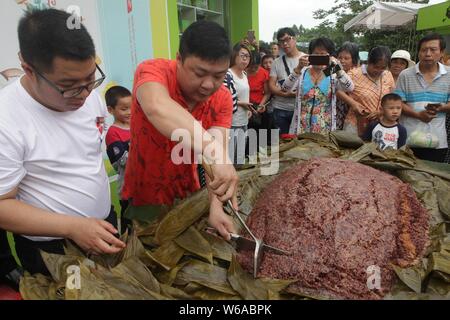 Les citoyens partagent un énorme zongzi, une boulette en forme de pyramide fait de riz gluant enveloppé dans des feuilles de roseau ou de bambou dans la ville de Liuzhou, Guangxi en Chine du sud Banque D'Images