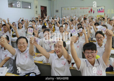 Des étudiants chinois qui vont se présenter à l'examen d'entrée du collège national annuel, également connu sous le gaokao, réagissent comme ils peuvent contenir jusqu'à 5 yuan billets en euros qui leur est donné comme Banque D'Images