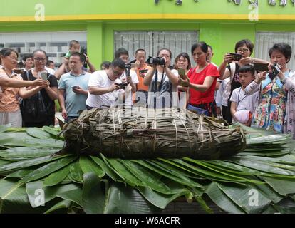 Les citoyens partagent un énorme zongzi, une boulette en forme de pyramide fait de riz gluant enveloppé dans des feuilles de roseau ou de bambou dans la ville de Liuzhou, Guangxi en Chine du sud Banque D'Images