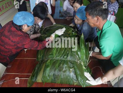 Les travailleurs chinois font une énorme zongzi, une boulette en forme de pyramide fait de riz gluant enveloppé dans des feuilles de roseau ou de bambou à Liuzhou city, South China's G Banque D'Images