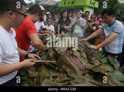 Les citoyens partagent un énorme zongzi, une boulette en forme de pyramide fait de riz gluant enveloppé dans des feuilles de roseau ou de bambou dans la ville de Liuzhou, Guangxi en Chine du sud Banque D'Images