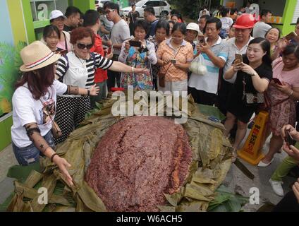 Les citoyens partagent un énorme zongzi, une boulette en forme de pyramide fait de riz gluant enveloppé dans des feuilles de roseau ou de bambou dans la ville de Liuzhou, Guangxi en Chine du sud Banque D'Images