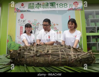 Les citoyens partagent un énorme zongzi, une boulette en forme de pyramide fait de riz gluant enveloppé dans des feuilles de roseau ou de bambou dans la ville de Liuzhou, Guangxi en Chine du sud Banque D'Images