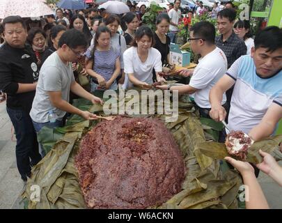 Les citoyens partagent un énorme zongzi, une boulette en forme de pyramide fait de riz gluant enveloppé dans des feuilles de roseau ou de bambou dans la ville de Liuzhou, Guangxi en Chine du sud Banque D'Images