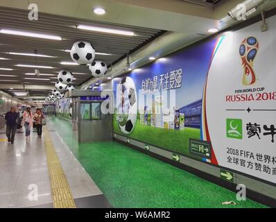 --FILE--passagers à pied passé une publicité de Mengniu Dairy pour la prochaine Coupe du Monde FIFA 2018 est vue à une station de métro de la ligne de métro de Beijing Banque D'Images