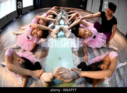 Un professeur de chinois donne aux jeunes filles de se dégourdir les jambes et plier leur corps pour apprendre des compétences de danse dans un centre de formation dans la ville de Bozhou, Moyen-Orient Banque D'Images