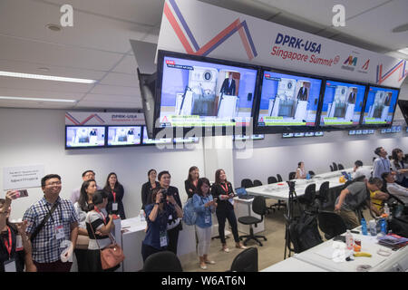 Centre des médias Les journalistes à l'affichage des écrans de surveillance que le président des États-Unis, l'atout de Donald deplanes comme son Air Force One arrive à la Paya Lebar Air Bas