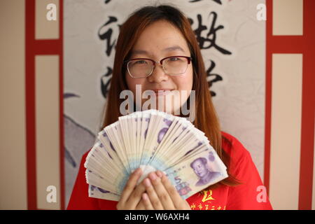 Un enseignant chinois montre 5-yuan billets qui sera donnée à ses élèves qui vont se présenter à l'examen d'entrée du collège national annuel, également connu sous le nom de gao Banque D'Images