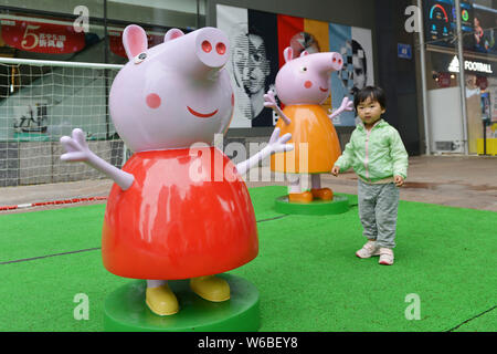 --FILE--un enfant pose pour des photos de sculptures en forme de personnages de la série animée Peppa Pig à Nanjing, ville de Jiangsu est p Banque D'Images