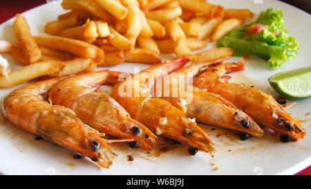 Les crevettes. Crevettes frites et pommes de terre sautées avec de la salade sur une assiette blanche. Cuisine dominicaine Banque D'Images