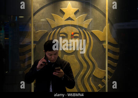 Un salaryman japonais ou un employé de bureau utilise un smartphone et un téléphone portable ordinaire alors qu'il attend devant le café Starbucks à Shibuya, Tokyo, Japon Banque D'Images