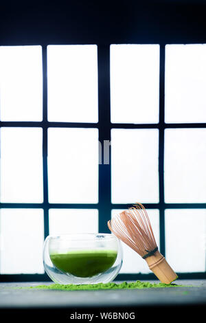 Thé vert matcha dans un bol à thé en verre double paroi avec un fouet en bambou. Arrière-plan de portes coulissantes Shoji, cérémonie traditionnelle japonaise Banque D'Images