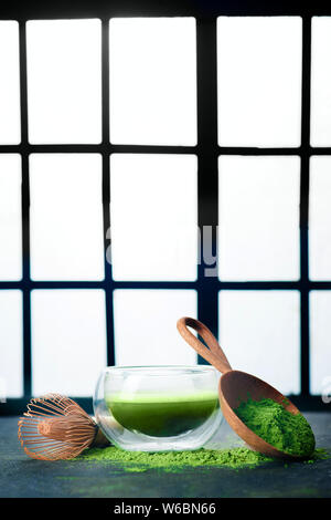 Thé vert matcha dans un bol à thé en verre double paroi avec un fouet en bambou. Arrière-plan de portes coulissantes Shoji, cérémonie traditionnelle japonaise Banque D'Images