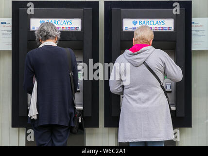Les femmes utilisent des distributeurs automatiques à l'extérieur d'une succursale de la Barclays Bank à Londres. Banque D'Images
