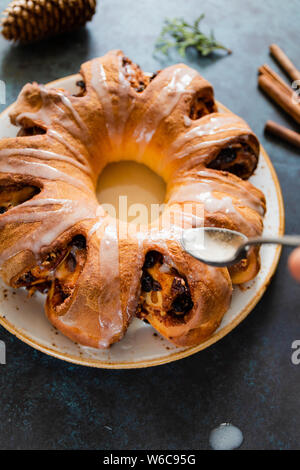 Bague plateau suédois gâteau de Noël à la cannelle, les pacanes et les raisins secs sur une chaude chandail tricoté. Le concept d'ambiance vacances d'hiver et de boulangerie. Banque D'Images