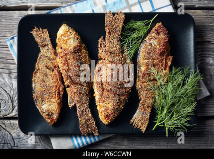 Close-up de carpes frites croustillantes le carassin noire sur une plaque rectangulaire sur une vieille table en bois, télévision lay Banque D'Images