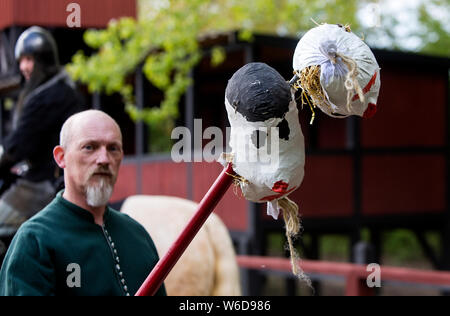 Un adjoint d'un knight montre deux têtes qui le chevalier butts avec sa lance au cours d'un tournoi de joutes en plein air, dans le centre médiéval de Nykøbing Falster, Danemark. Avant la tête artificielle a été introduit dans les temps anciens du vrai chefs d'ennemis décapités ou des criminels a été utilisé. Le centre médiéval est un musée vivant, expérimental qui illustre le Moyen Âge danois à la 14e et 15e siècle. Il est conçu comme une ville typique marché danois avec des artisans, un port avec bateaux et navires, et une place de marché. Le Centre d'employés et de bénévoles sont habillés en costumes de l'époque, ils liv Banque D'Images