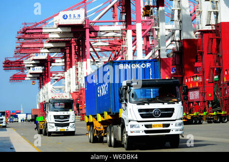 Les conteneurs de transport des camions pour être expédiés à l'étranger, sur un quai du port de Qingdao en Qingdao city, province de Shandong en Chine orientale, le 13 avril 2018. Ch Banque D'Images