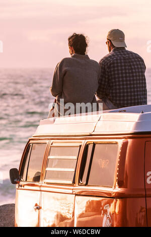 Un couple assis sur le dessus de leur camping-car Volkswagen VW profitant de la lumière du soir à dans Fistral Newquay en Cornouailles. Banque D'Images