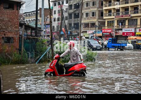 Srinagar, J&K, de l'Inde. 1er août 2019. Un homme pousse son scooter à travers un chemin d'eau- connecté après les fortes pluies de Srinagar.pluies diluviennes ont causé l'engorgement dans de nombreux domaines de Srinagar exposant le mauvais drainage de la ville. Le temps le ministère a prévu de fortes pluies pour les prochains jours l'ensemble de la région. Credit : Saqib Majeed/SOPA Images/ZUMA/Alamy Fil Live News Banque D'Images