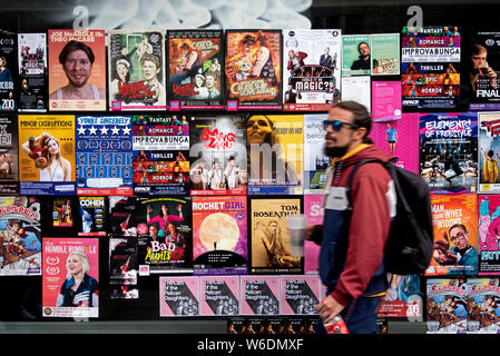 Un jeune homme marchant par affiches publicitaires pour Edinburgh Fringe Festival montre. Edinburgh, Ecosse, Royaume-Uni. (With motion blur) Banque D'Images
