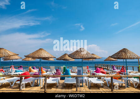 Des parasols et des chaises longues de plage multicolores sur un pont par la mer Égée dans l'ouest de la Turquie Banque D'Images