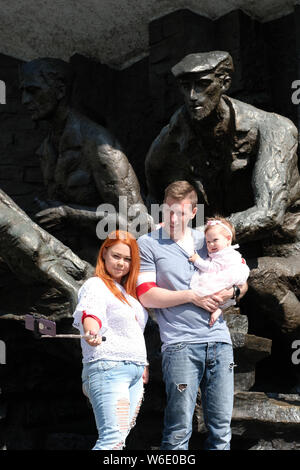 Pologne Varsovie - Jeudi 1 Août - une jeune famille portant fièrement un brassard patriotique posent devant le monument du soulèvement de Varsovie à Varsovie que la Pologne commémore le 75e anniversaire de l'Insurrection de Varsovie ( Powstanie Warszawskie ) contre l'armée allemande d'occupation au 1er août 1944 - l'Insurrection de Varsovie les combattants de la résistance de l'Armée de l'Intérieur (Armia Krajowa - AK ) lutté sur pendant 63 jours contre les forces nazies avant capitulation que l'avancement de l'armée soviétique a attendu de l'autre côté de la rivière Vistule. Photo Steven Mai / Alamy Live News Banque D'Images