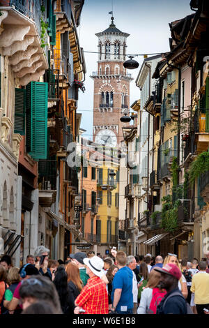 À Vérone, Italie, la foule des touristes à la mode, colorée rue piétonne Via Giuseppe Mazzini. Le 12ème tour des Lamberti dépasse. Banque D'Images